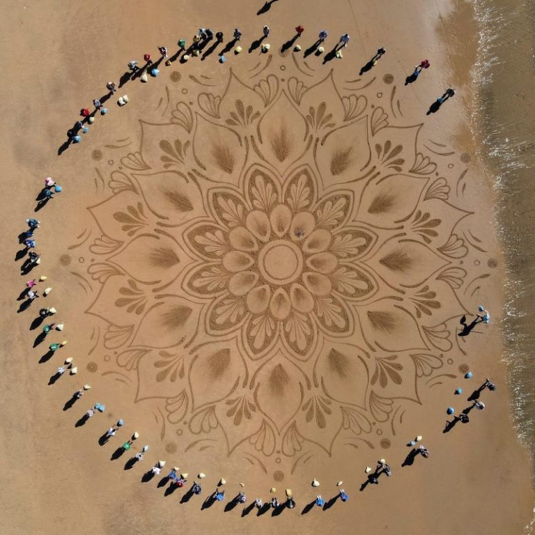 Voluntarios onubenses ayudan a Quirze Codina a dibujar un mandala gigante en la playa de Mazagón